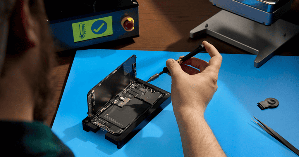 a man repairing an open iPhone with a screwdriver