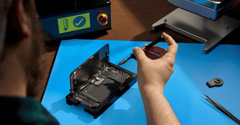 a man repairing an open iPhone with a screwdriver