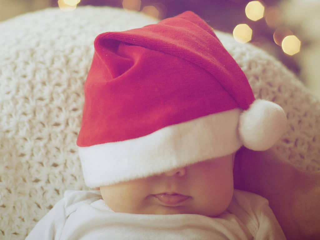 Sleepy baby with a Santa hat covering their face